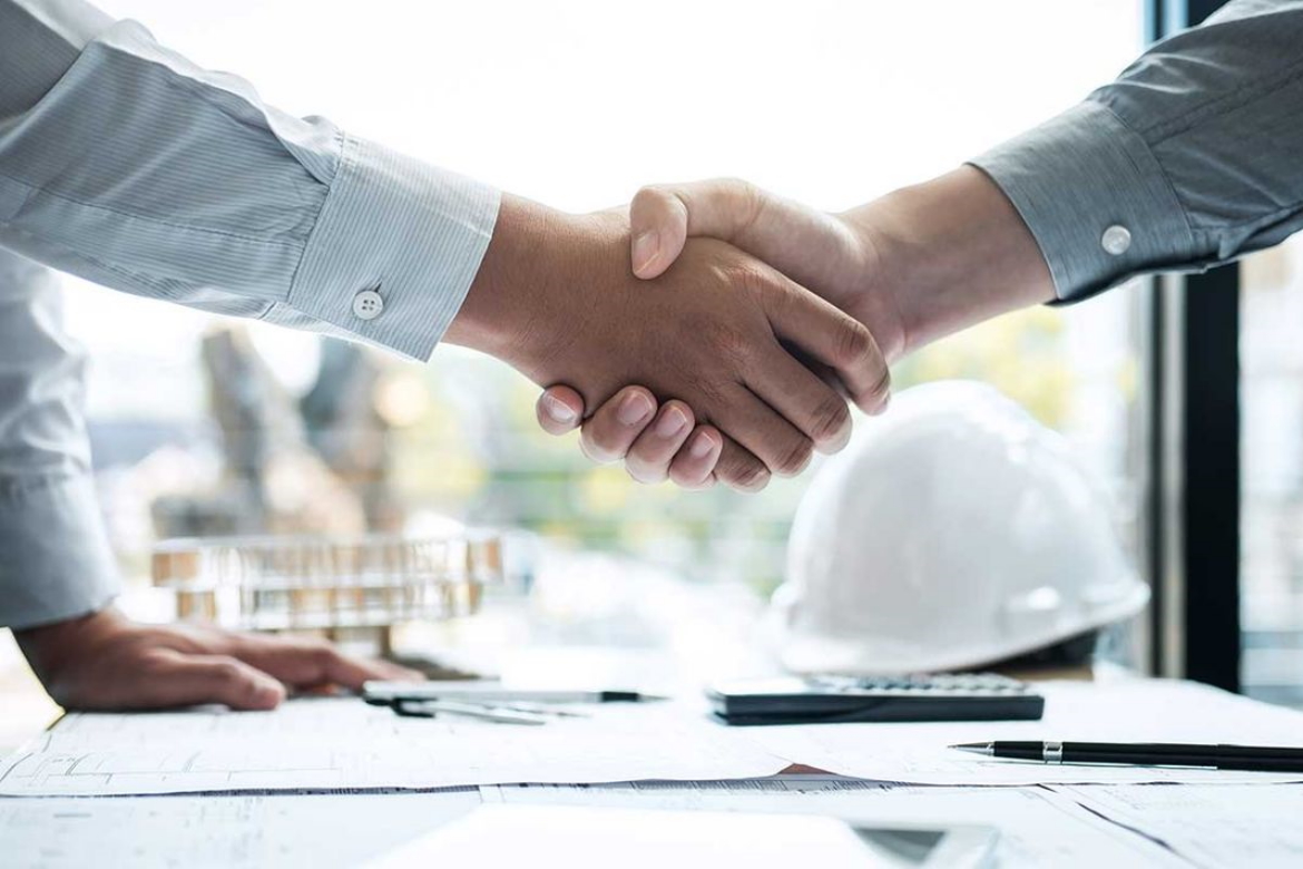 handshake over desk of construction documents